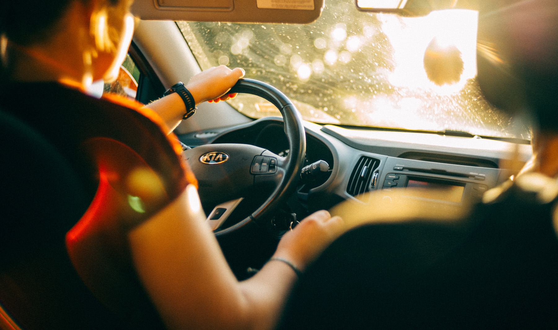 Woman driving a Kia, sunlight windshield